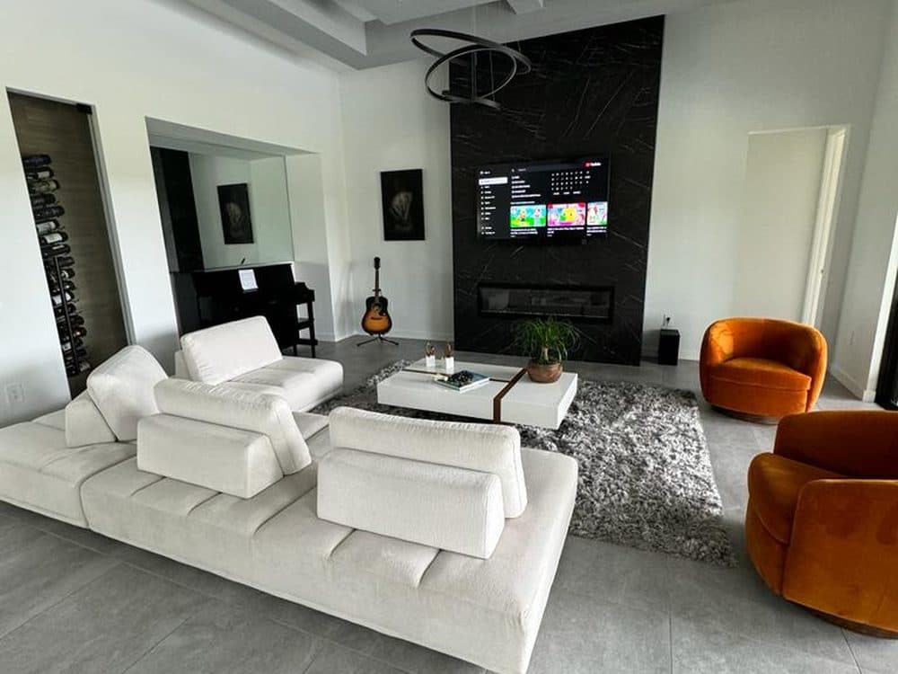 Interior repaint — open living room with a coffered ceiling, black marble fireplace, and warm white walls.