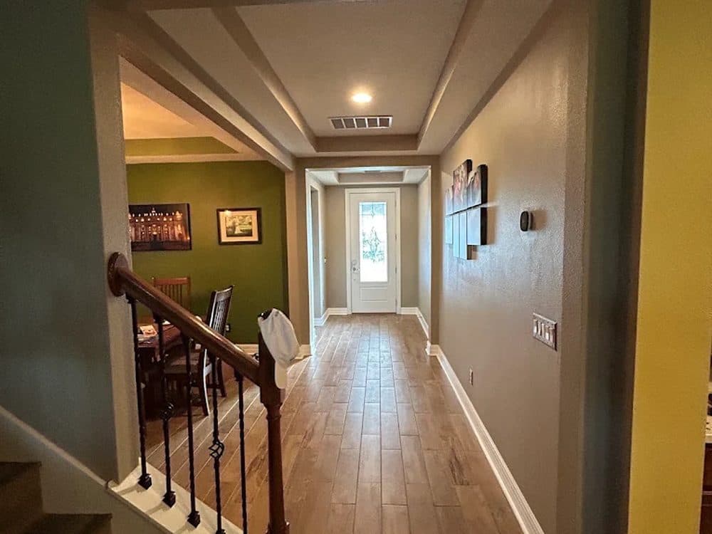 Interior repaint — a stair hall with an olive accent wall and white risers and trim.